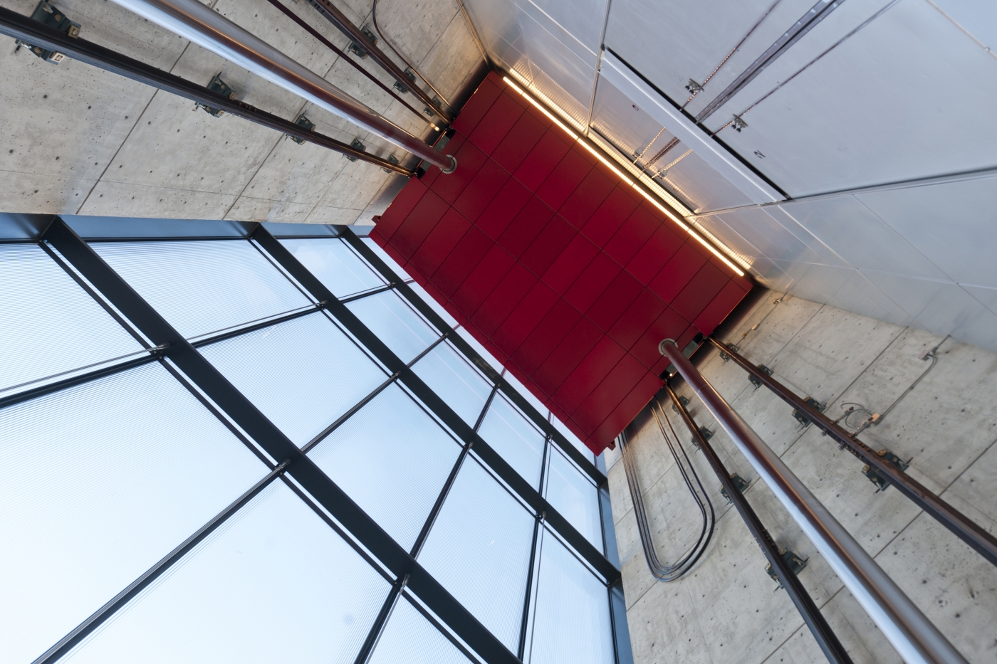 looking up at the gallery's moving room elevator covered in bright red panels from below