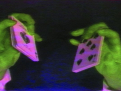 close up of two green hands each holding pink playing cards