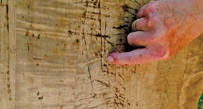 video still showing a close up of a hand with the index finger making an invisible mark on a piece of plywood